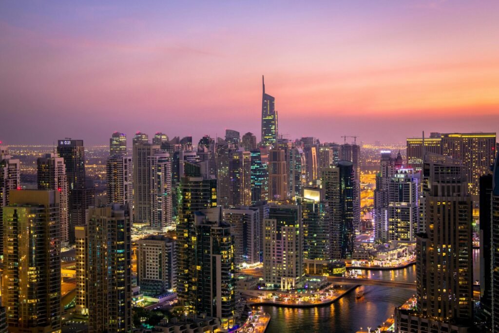 Destination City skyline at dusk with illuminated skyscrapers and a winding waterfront canal.