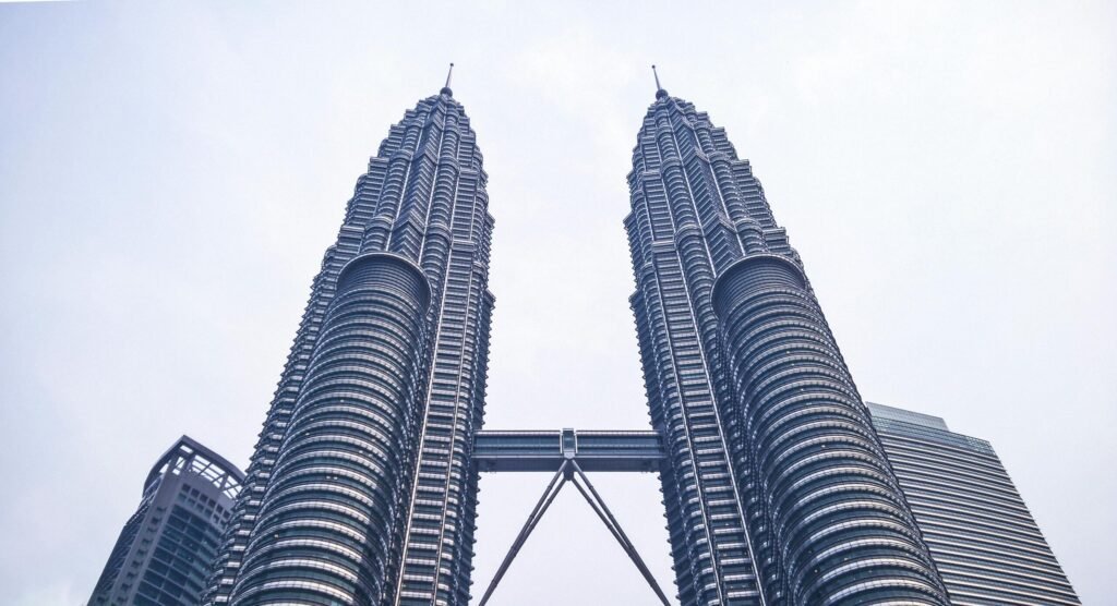 Petronas Twin Towers in Kuala Lumpur viewed from below, showing the two identical skyscrapers connected by a skybridge.