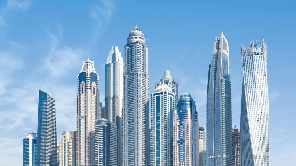 Modern city skyline with tall glass skyscrapers under a clear blue sky.
