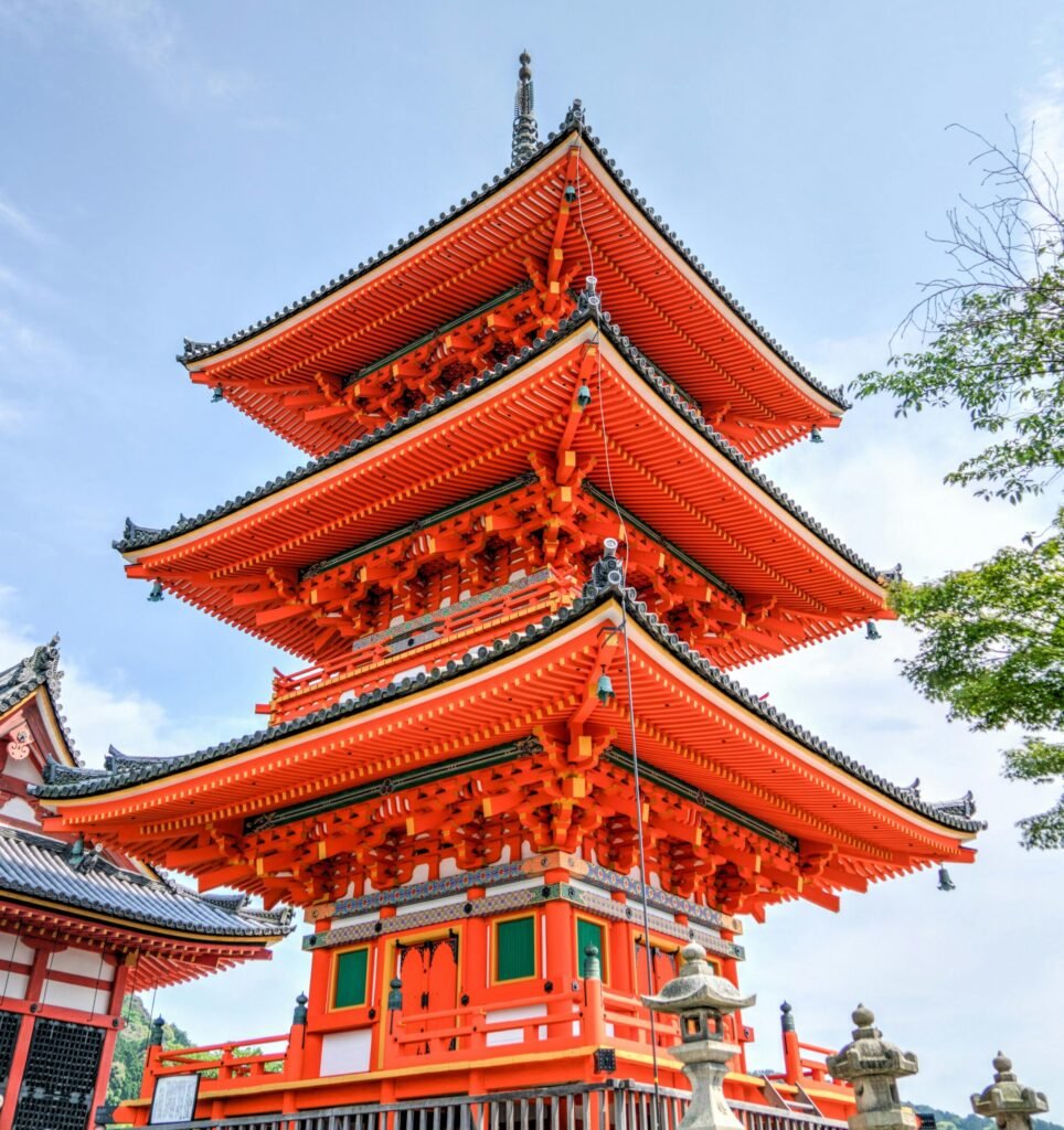 Destination Traditional multi-tiered Japanese pagoda with red wooden architecture under a blue sky.