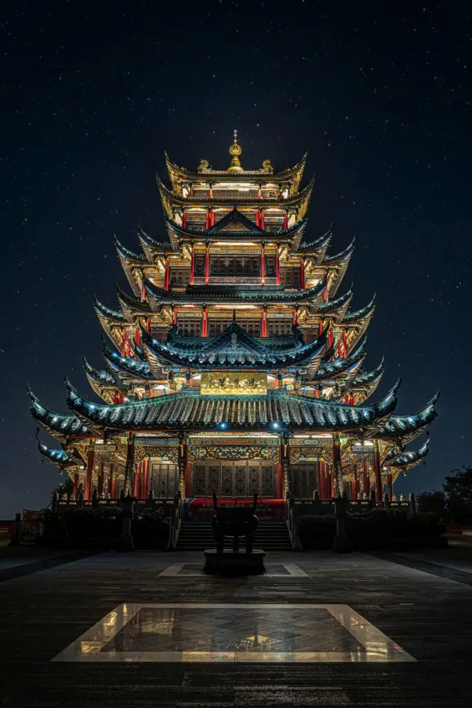 Destination Illuminated multi-tiered traditional pagoda temple at night under a starry sky.